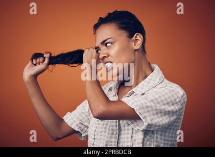 Ich brauche, dass ihr etwas stärker seid. Eine junge Frau mit nassem Haar, die vor einem orangen Hintergrund posiert. Stockfoto