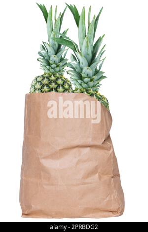 Nahaufnahme einer braunen Einkaufstasche aus Papier mit frischen, reifen Ananasfrüchten, isoliert auf weißem Hintergrund. Konzept der Stärkung des Immunsystems. Gesunde Ernährung. Tropische Früchte. Stockfoto