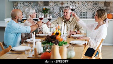 Freunde wie Sie sind jeden Tag des Jahres etwas Besonderes. Zwei glückliche Paare sitzen zum Mittagessen und toasten zu Hause mit Weingläsern. Stockfoto