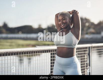 Sei deine eigene Inspiration. Eine attraktive junge Frau, die sich draußen ausdehnt. Stockfoto