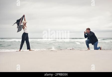 Streich eine Pose, Baby. Ein Mann, der Fotos von seiner Freundin macht, während er Zeit am Strand verbringt. Stockfoto