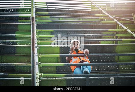 Erteilen von Befehlen während der Durchführung von Inspektionen. Eine junge Frau, die auf einer Baustelle ein Walkie-Talkie benutzt. Stockfoto