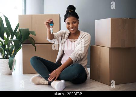 Es ist endlich meine. Porträt einer jungen Frau, die die Schlüssel zu ihrem neuen Zuhause hält. Stockfoto