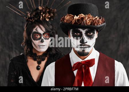 Feiern der Vorfahren weve verloren. Verkürztes Porträt eines liebevollen jungen Paares in ihren mexikanischen Halloween-Kostümen. Stockfoto