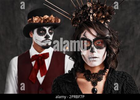 Sich an die Verlorenen zu erinnern. Verkürztes Porträt eines liebevollen jungen Paares in ihren mexikanischen Halloween-Kostümen. Stockfoto