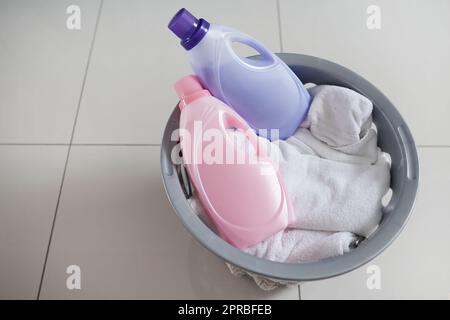 Weichspüler für Wäschetage, an denen Sie sich besonders fühlen. Aufnahme eines Waschkorbs mit sauberer Wäsche und zwei Flaschen Weichspüler. Stockfoto