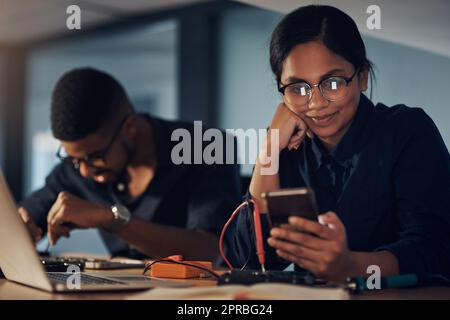 Computer reagiert nicht Keine Sorge, wird sie. Ein junger Techniker, der ein Smartphone benutzt, während er Computerhardware repariert. Stockfoto