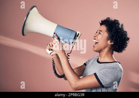 Sagen Sie es laut und stolz. Studioaufnahme einer Frau, die über ein Megaphon spricht. Stockfoto