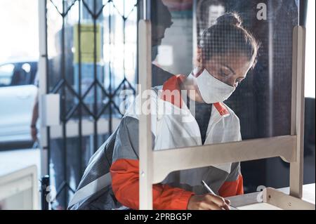 Eine junge Frau, die Papierkram an der Rezeption eines Fitnessstudios ausfüllt. Stockfoto