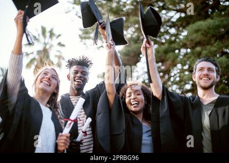 Bildung ist der Schlüssel, um die goldene Tür der Freiheit zu öffnen. Portrait einer Gruppe von Studenten, die am Tag der Abschlussfeier Hüte hochhielten. Stockfoto