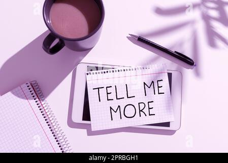 Inspiration mit Schild „Erzählen Sie mir mehr“. Ein Wort, das in Einem Telefonat geschrieben wurde, um ein Gespräch zu beginnen Weitergeben von mehr Wissen Aktuelle Nachrichten, die auf „Note Over Tablet on Desk“ mit Kaffee, Stift und Notizbuch geschrieben wurden Stockfoto