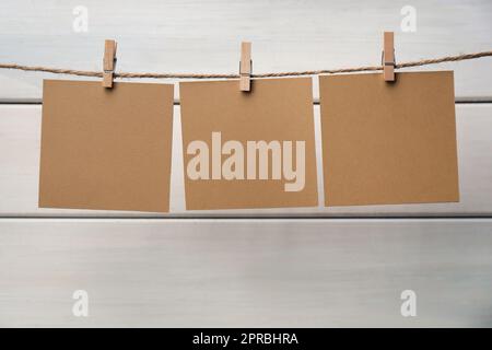 Kleiderschränke mit leeren Notizzetteln auf Garn auf weißem Holzhintergrund. Platz für Text Stockfoto