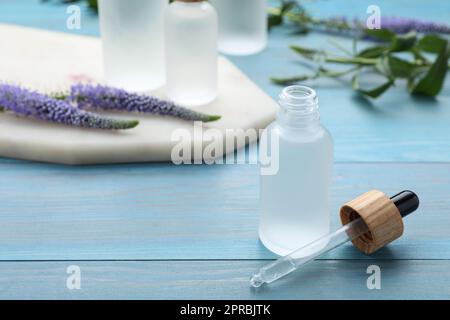 Flasche ätherisches Öl auf hellblauem Holztisch, Nahaufnahme. Platz für Text Stockfoto