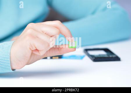 Eine Frau, die eine Micro-sim-Karte in der Hand hält Stockfoto