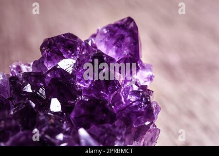 Wunderschöner lilafarbener Amethyst-Edelstein auf verschwommenem braunem Hintergrund, Nahaufnahme Stockfoto