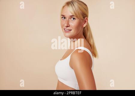 Wunderschöne blonde Frau mit Sommersprossen, die im Studio vor pastellfarbenem Hintergrund posiert Stockfoto