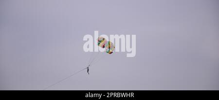 Eine Person, die unter einem Gleitsegel am Himmel in Jomtien, Pattaya, Thailand gleitet. Stockfoto