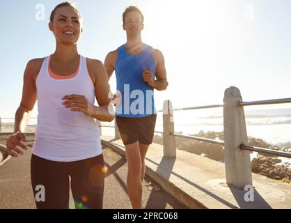 Bis ans Limit. Ein junges Paar, das auf der Promenade joggt. Stockfoto