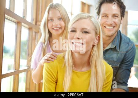 Am glücklichsten, wenn sie zusammen sind. Porträt einer glücklichen jungen Familie, die sich zu Hause anfreundet. Stockfoto
