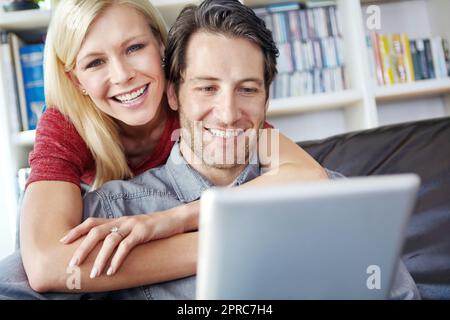 Ein romantisches Restaurant zum Abendessen zu finden. Eine attraktive junge Frau, die ihren Freund umarmt, während er ein digitales Tablet benutzt. Stockfoto