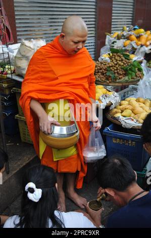 Ein thailändischer buddhistischer Mönch segnet die Einheimischen und empfängt Almosen im Rahmen eines morgendlichen Rituals. Foto in Bangkok, Thailand. Stockfoto