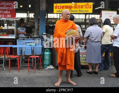 Ein thailändischer buddhistischer Mönch segnet die Einheimischen und empfängt Almosen im Rahmen eines morgendlichen Rituals. Foto in Bangkok, Thailand. Stockfoto