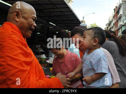 Ein thailändischer buddhistischer Mönch segnet die Einheimischen und empfängt Almosen im Rahmen eines morgendlichen Rituals. Foto in Bangkok, Thailand. Stockfoto