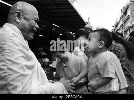 Ein thailändischer buddhistischer Mönch segnet die Einheimischen und empfängt Almosen im Rahmen eines morgendlichen Rituals. Foto in Bangkok, Thailand. Stockfoto