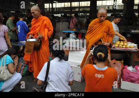 Ein thailändischer buddhistischer Mönch segnet die Einheimischen und empfängt Almosen im Rahmen eines morgendlichen Rituals. Foto in Bangkok, Thailand. Stockfoto