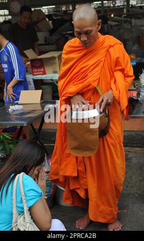 Ein thailändischer buddhistischer Mönch segnet die Einheimischen und empfängt Almosen im Rahmen eines morgendlichen Rituals. Foto in Bangkok, Thailand. Stockfoto