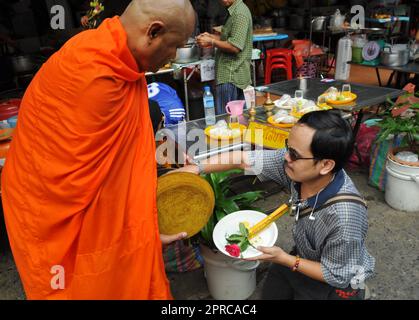 Ein thailändischer buddhistischer Mönch segnet die Einheimischen und empfängt Almosen im Rahmen eines morgendlichen Rituals. Foto in Bangkok, Thailand. Stockfoto