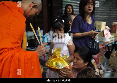 Ein thailändischer buddhistischer Mönch segnet die Einheimischen und empfängt Almosen im Rahmen eines morgendlichen Rituals. Foto in Bangkok, Thailand. Stockfoto