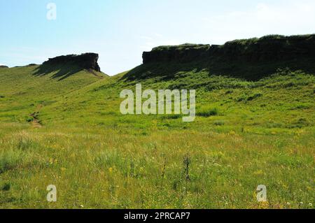 Die Überreste einer alten Steinmauer, die auf einem Hügel in einem malerischen Tal mit Sonnenlicht verläuft. Berghütten, Chakassia, S. Stockfoto