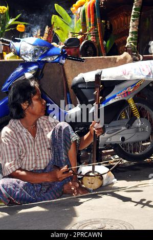 Ein älterer Thailänder, der die Saw Duang spielte, verbeugte das Saiteninstrument auf der Straße im Zentrum von Bangkok, Thailand. Stockfoto