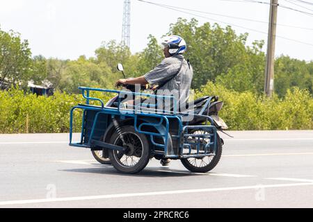 BANGKOK, THAILAND, MÄRZ 24 2023, ein Motorradfahrer mit Wagen fährt in die entgegengesetzte Richtung auf die Straße Stockfoto