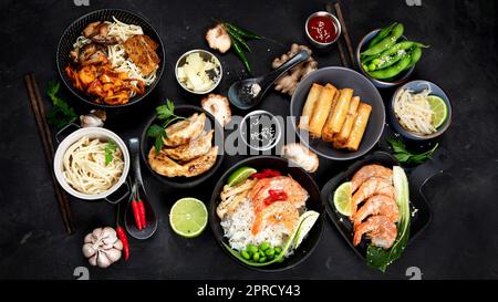 Verschiedene asiatische Gerichte auf schwarzem Hintergrund, Draufsicht. Asiatisches Speisenkonzept. Stockfoto