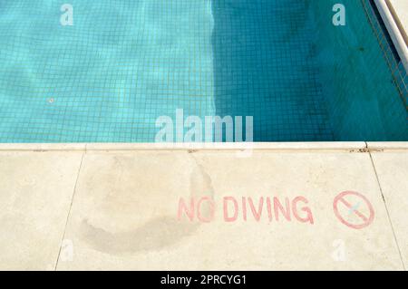 Rote Beschriftung kein Tauchen zur Sicherheit am Hintergrund des Pools in einem tropischen warmen Meeresresort und Kopierbereich. Stockfoto