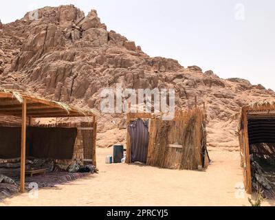 Eine fadenscheinige, verfallene, zerbrechliche, arme Wohnung, ein Beduinengebäude aus Stroh, Zweige in einer sandigen heißen Wüste im Sand des Parkis Stockfoto