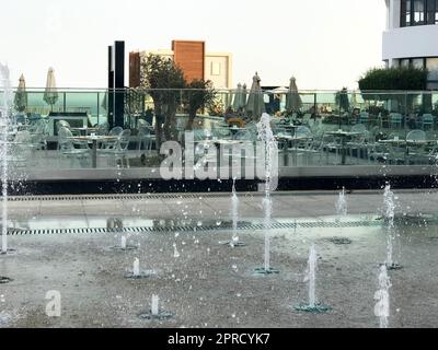 Ein kleiner singender Springbrunnen im Freien, auf der Straße. Wassertropfen, Wasserstrahlen, die während des Fluges in der Luft gefroren sind. Stockfoto