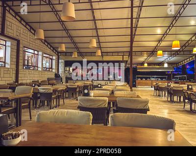 Rest der Touristen in einem teuren Hotel. Das Essen wird im Speisesaal im Freien serviert. Cafeteria-Möbel, gemütliche Stoffstühle und Korbtische Stockfoto