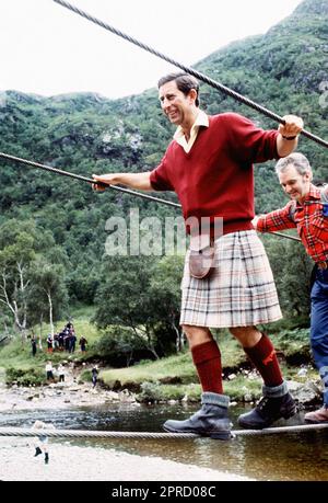 Dateifoto vom 18. Dezember 08/87, auf dem der Prince of Wales mit dem Lochaber Mountain Rescue Team eine 2 cm breite Drahtbrücke überquert, während einer Wanderung in den Ausläufern von Ben Nevis. Die Nachrichtenagentur der PA hat Fotos von jedem Jahr des Königs zusammengestellt, um Karls III. Krönung zu feiern. Ausgabedatum: Donnerstag, 27. April 2023. Stockfoto