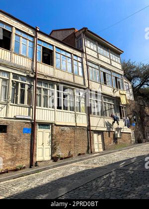 Alte Gebäude mit Holzbalkonen und Fenstern an der Straße mit einer Neigung von 45 Grad, veraltete Architektur. Stockfoto