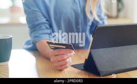 Wenn es ein Schnäppchen ist, worauf warten Sie dann noch? Eine Frau, die ihre Kreditkarte in der Hand hält, während sie auf ihrem digitalen Tablet surft. Stockfoto