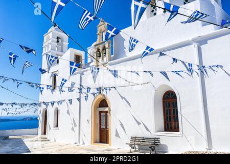 Weiß getünchtes Gebäude mit griechischem Flaggengewölbe auf Milos Island Griechenland in der Nähe des Meeres Stockfoto