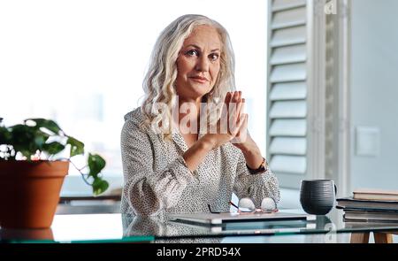 Als Geschäftsfrau muss ich weiterarbeiten. Verkürztes Porträt einer attraktiven Geschäftsfrau, die mit aneinander gereihten Händen von zu Hause aus arbeitet. Stockfoto