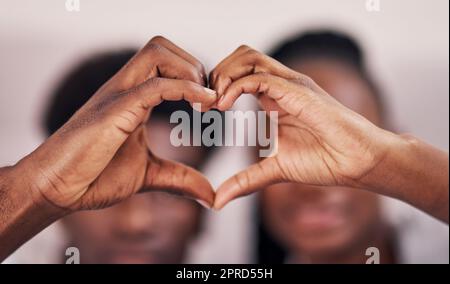 Liebe macht die Welt rund. Ein junges Paar bildet eine Herzform, indem es sich ihre Hände verbindet. Stockfoto