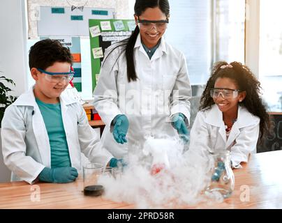 Wann hatten Spaß lernten. Ein entzückender kleiner Junge und ein Mädchen, die ein wissenschaftliches Experiment mit ihrem Lehrer in der Schule durchführten. Stockfoto