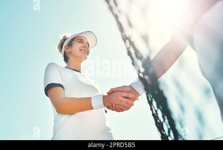 Seien Sie anmutig in Ihren Siegen und in Ihren Niederlagen. Eine attraktive junge Tennisspielerin schüttelt sich die Hände mit einem Gegner im Freien auf dem Platz. Stockfoto