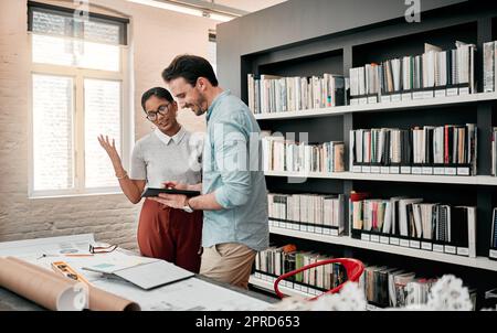 Wer wusste, dass Tablets alles so einfach machten. Zwei aufstrebende junge Architekten, die ein digitales Tablet nutzen, während sie in einem modernen Büro zusammenarbeiten. Stockfoto