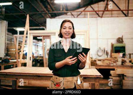 Wir werben für jedes Stück, das wir online fertigstellen. Eine Tischlerin mit einem digitalen Tablet in ihrer Werkstatt. Stockfoto